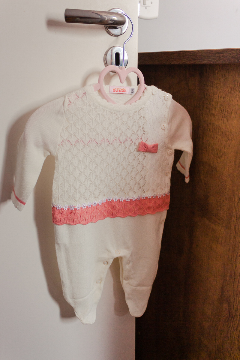foto detalhe da roupa da bebe rosa e branca pendurada no quarto infantil no ensaio lifestyle de família na cidade de Sp