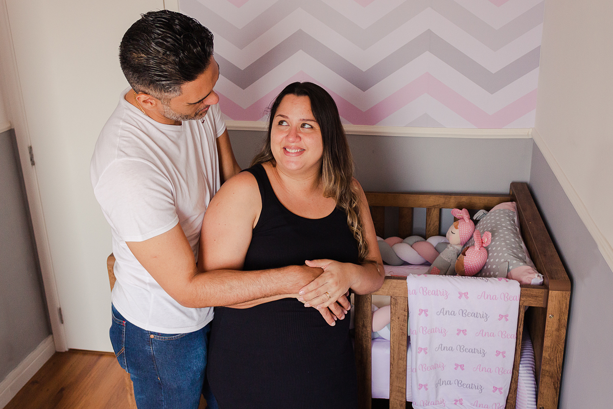 Foto do casal mãe e pai a espera da bebe menina se olhando no quarto no ensaio de gestante na cidade de Sp