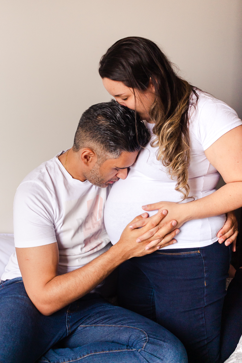foto de casal abraçados e o pai beijando a barrida da mamãe de gravida no ensaio de gestante em Sp