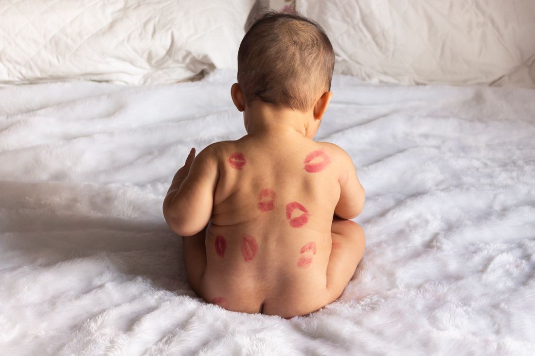 foto infantil de bebe deitado na cama do quarto dos pais pelado com beijo de batom no ensaio de família na cidade de Sp
