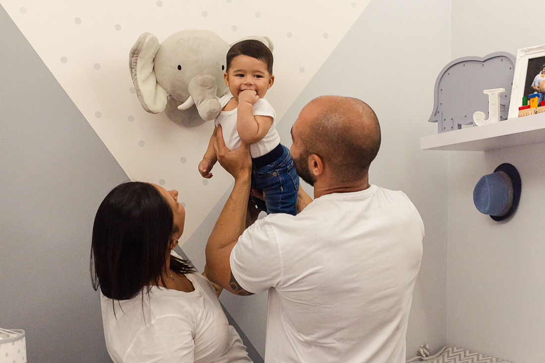 foto de pai e mãe no quarto com decoração de elefante brincando com o o filho menino no ensaio de família na cidade de Sp