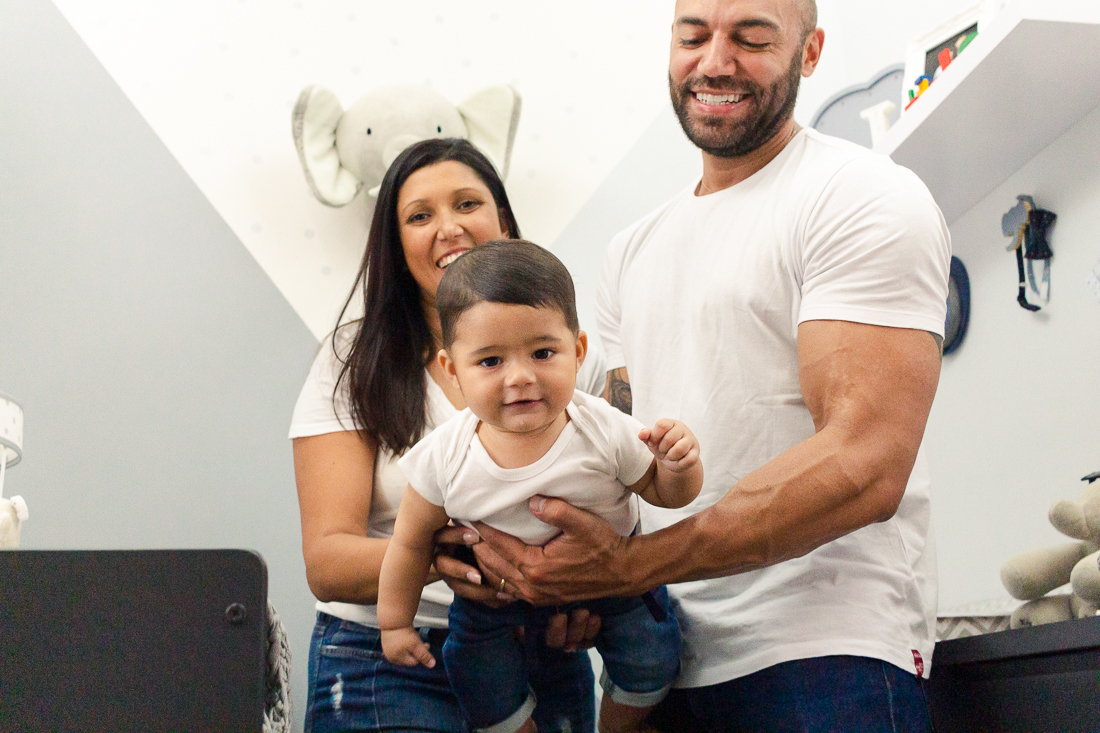 foto de pai e mãe no quarto com decoração de elefante segurando o filho menino no ensaio de família na cidade de Sp