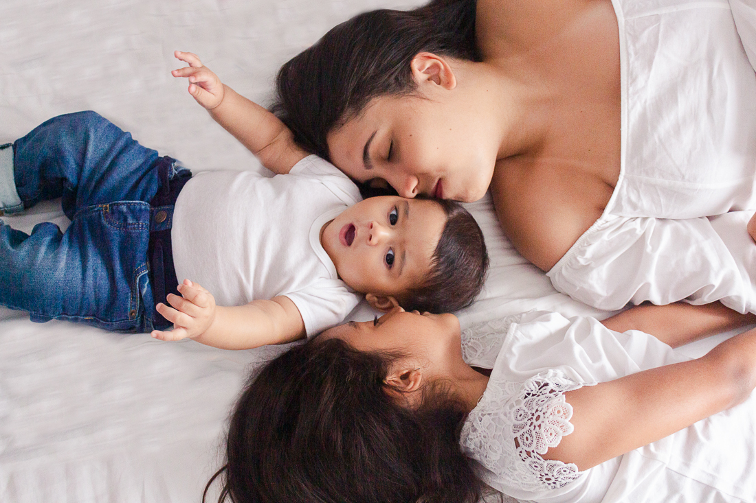 foto de irmã dando beijo no bebe irmão deitado na cama no ensaio lifestyle de família no Jd Primavera na cidade de SP