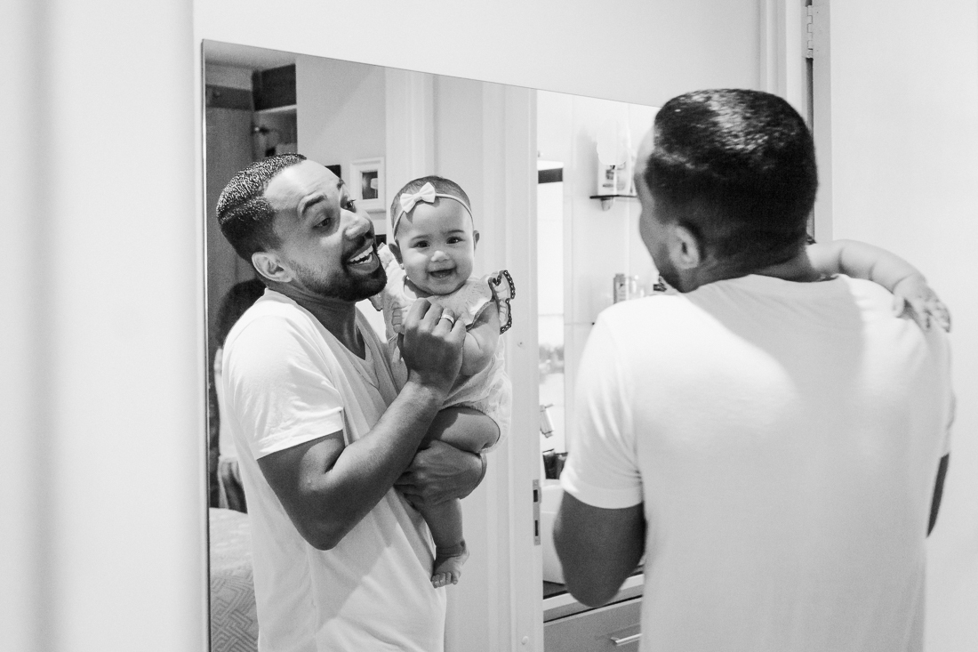 Foto de pai e filha sorrindo em frente ao espelho no ensaio de família na zona leste na cidade de São Paulo