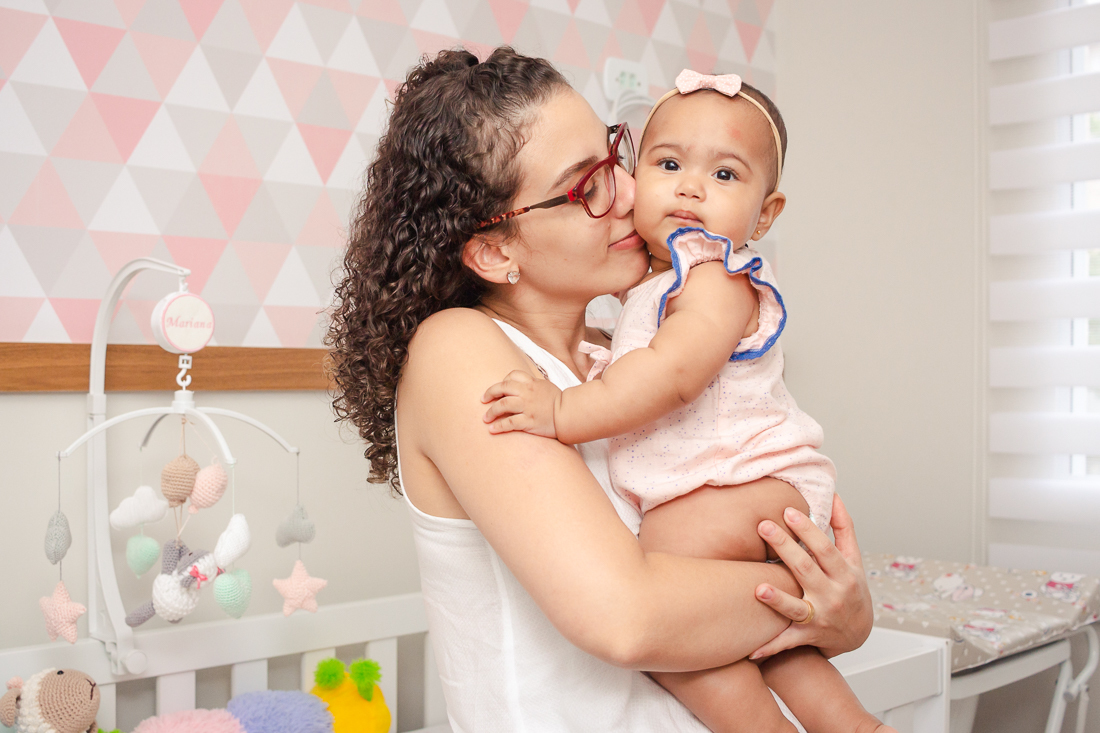 foto de mãe cheirando e fazendo carinho na filha no quarto da família 