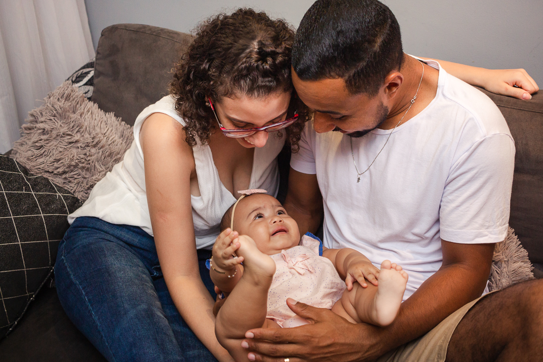 foto de pais com filha no colo na sala no ensaio de família na cidade de São Paulo