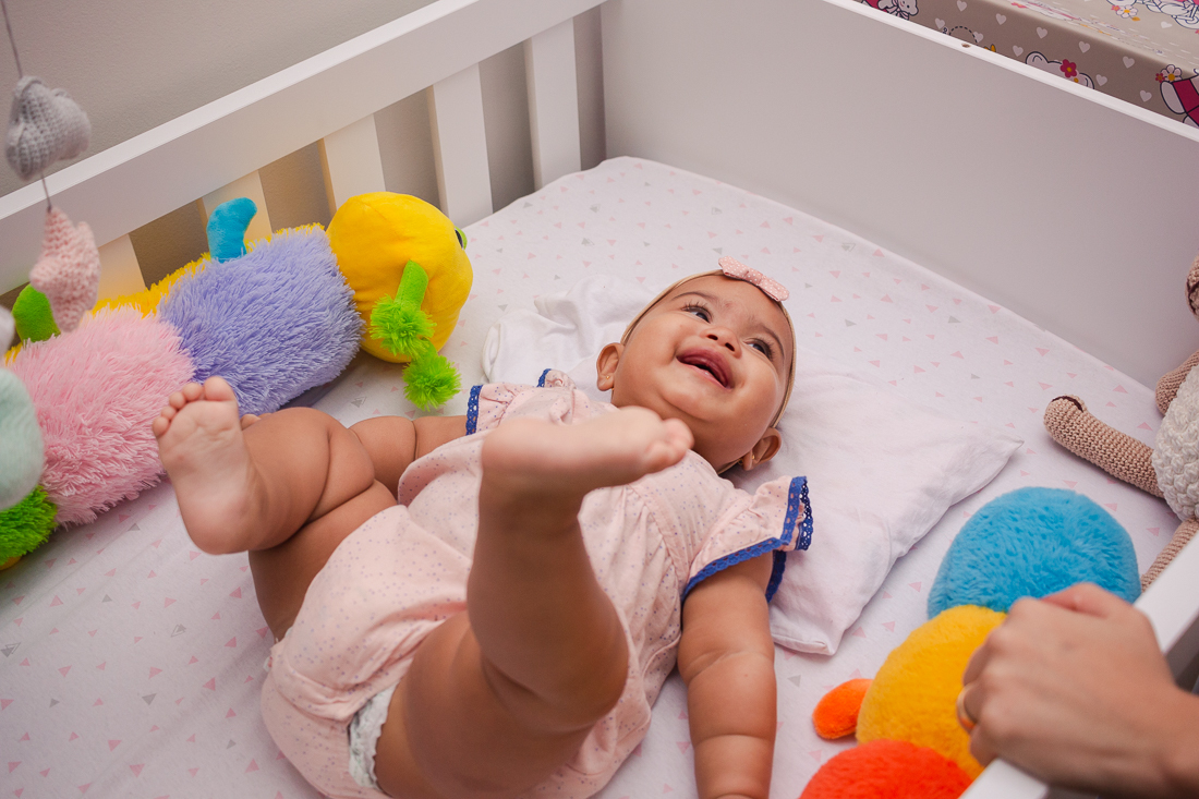 foto de criança deitada no berço sorrindo para a mãe no quarto no no ensaio em casa na cidade de Sp