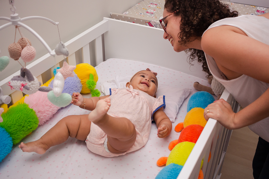 foto de criança deitada no berço sorrindo para a mãe no quarto no no ensaio em casa na cidade de Sp