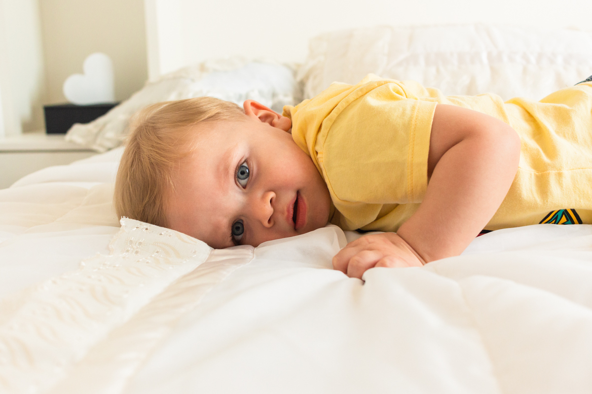 foto infantil de menino deitado na cama no ensaio de família em Itaquera na cidade de São Paulo