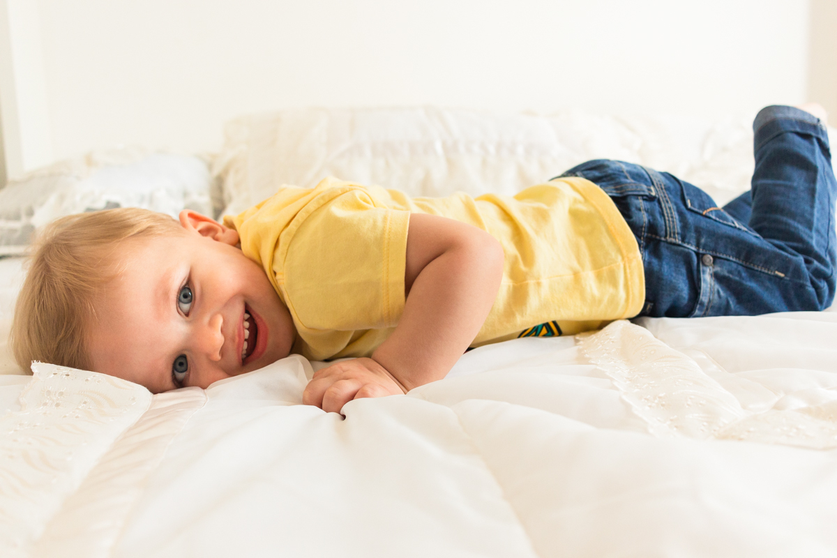 foto infantil de menino deitado na cama no ensaio de família em Itaquera na cidade de São Paulo