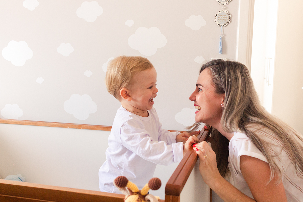 foto de criança dentro do do berço sorrindo para a mãe no ensaio de família em casa na cidade de Sp