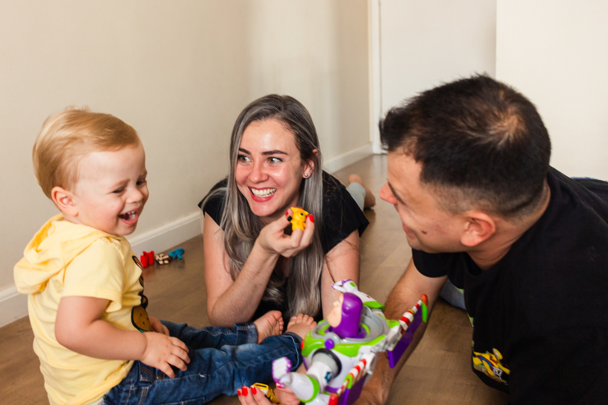 foto de criança com os pais brincando no chão da sala no ensaio de família em casa na cidade de Sp