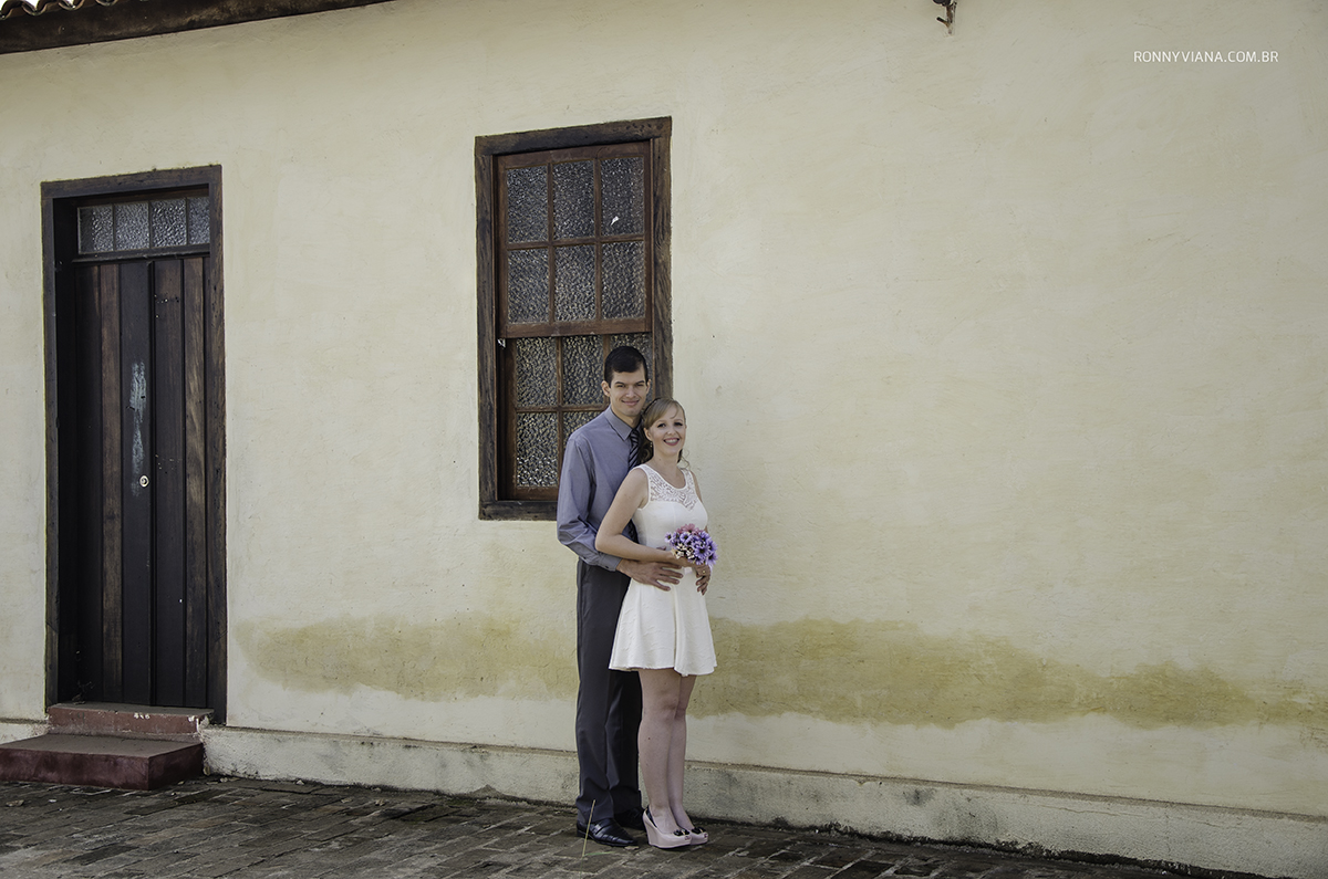 casal abraçado vestido basico branco buque azul, camisa social e calça social azul