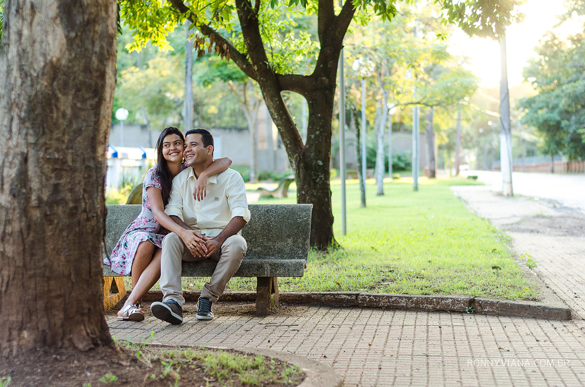fotos de ensaio de casal sentado no banco com arvores ao redor
