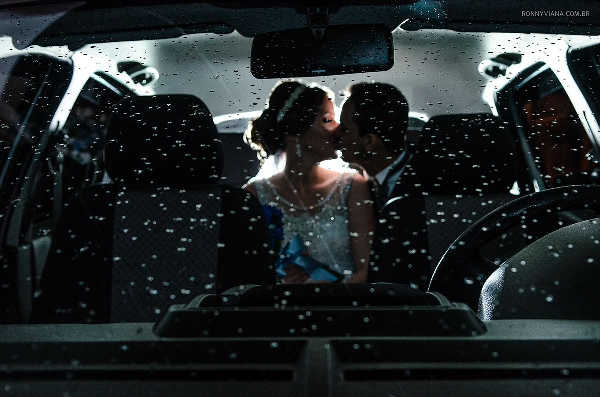noivos beijando após cerimonia dentro do carro gotículas de chuva no para-brisa