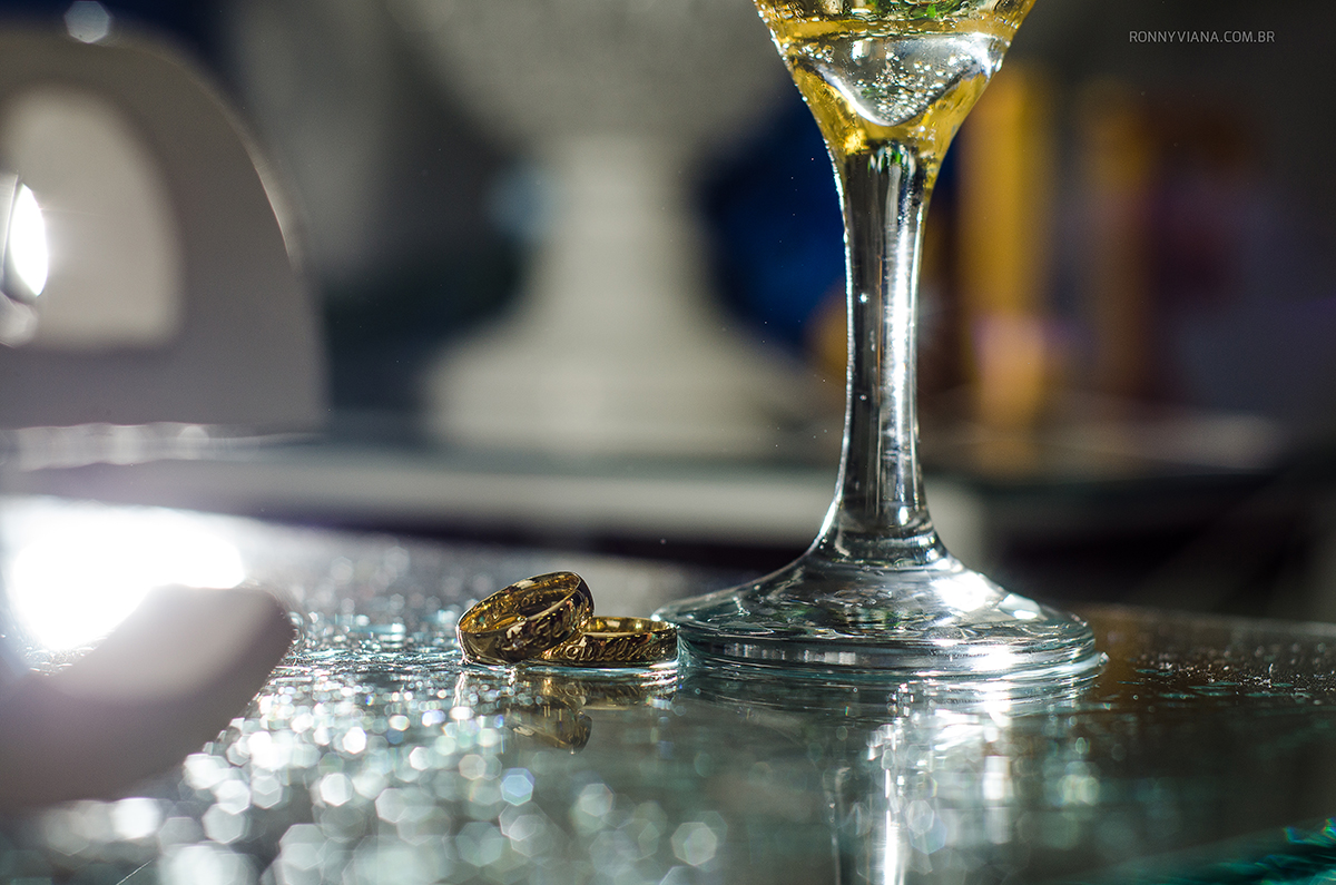 foto das alianças com taça de champanhe