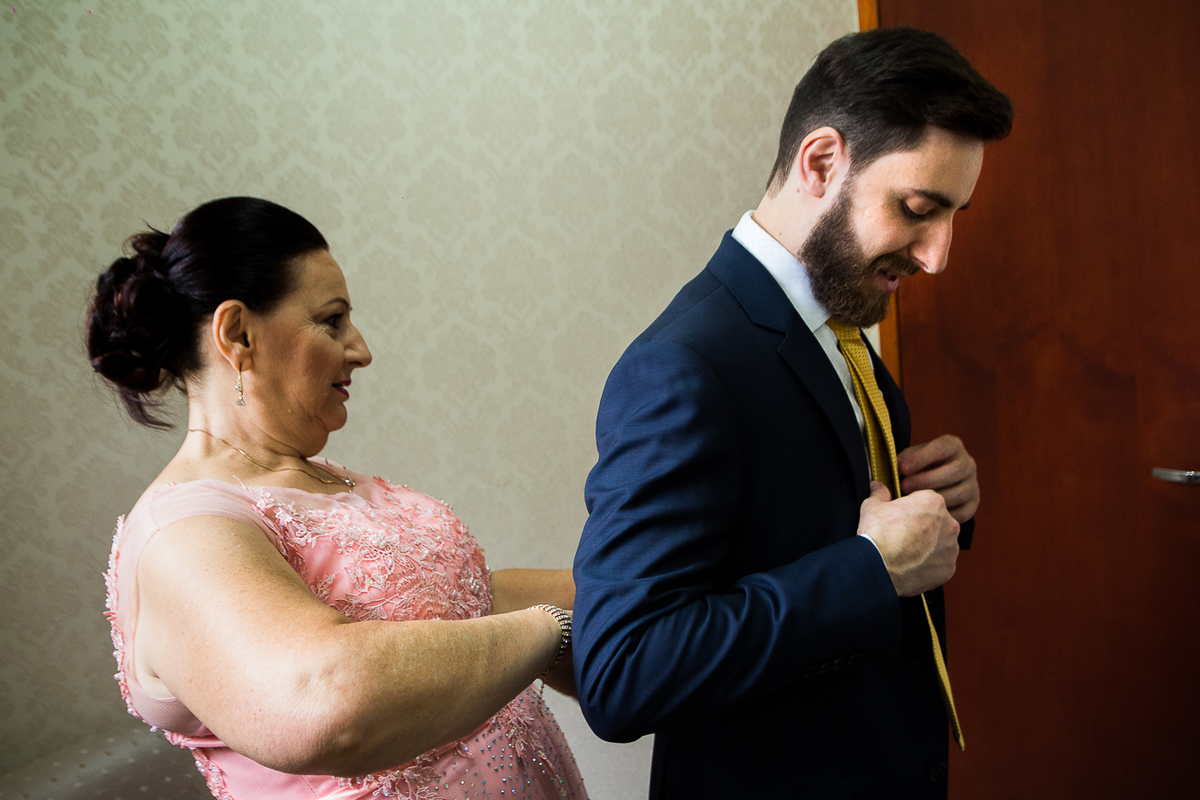 mae do noivo ajustando o paleto e gravata