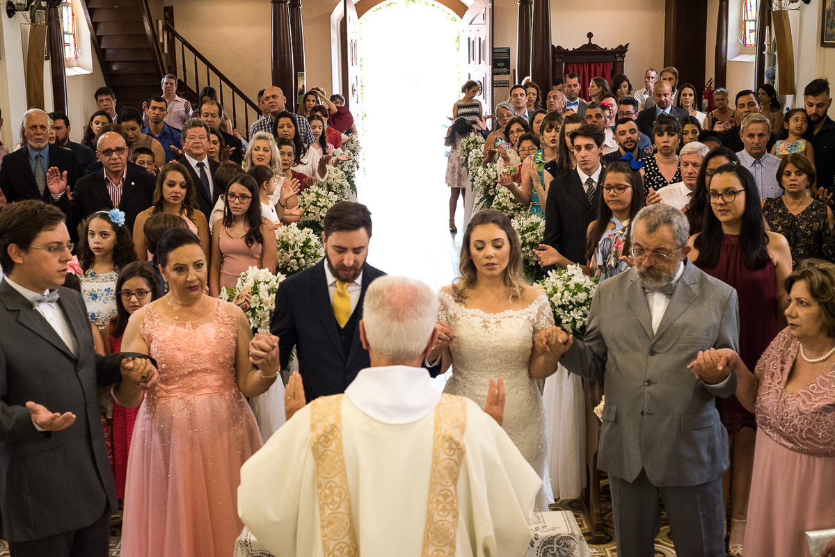 Padre, pais e noivos rezando com a famlia no altar