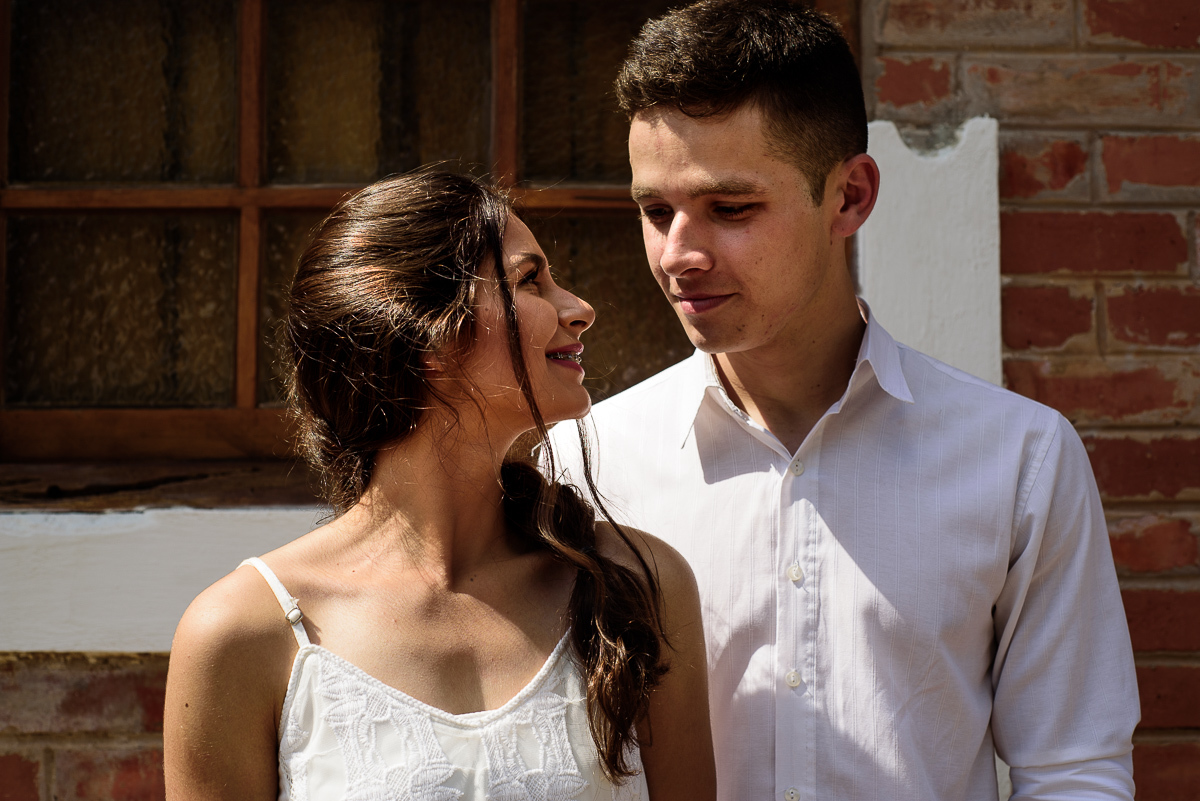 casal trocando olhares na frente de uma parede antiga durante o dia