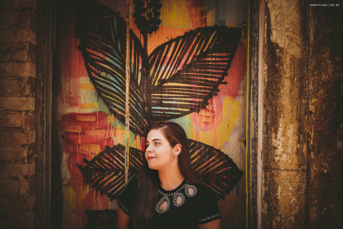 retrato feminino com parede pichada e blusa preta