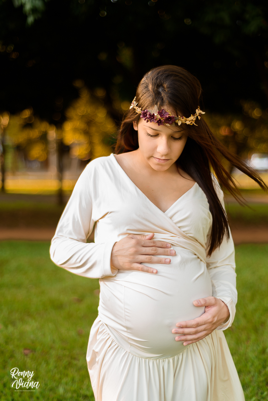 Gestante olhando sua barriga com vestido da loja Amada Mãe modelo calda de sereia branco fotografia por Ronny Viana