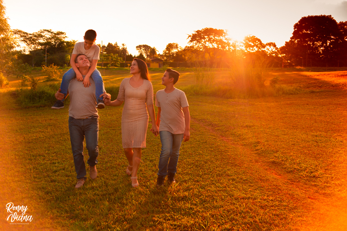 filho no colo do pai caminhando no por do sol com roupas de grife em Piracicaba SP