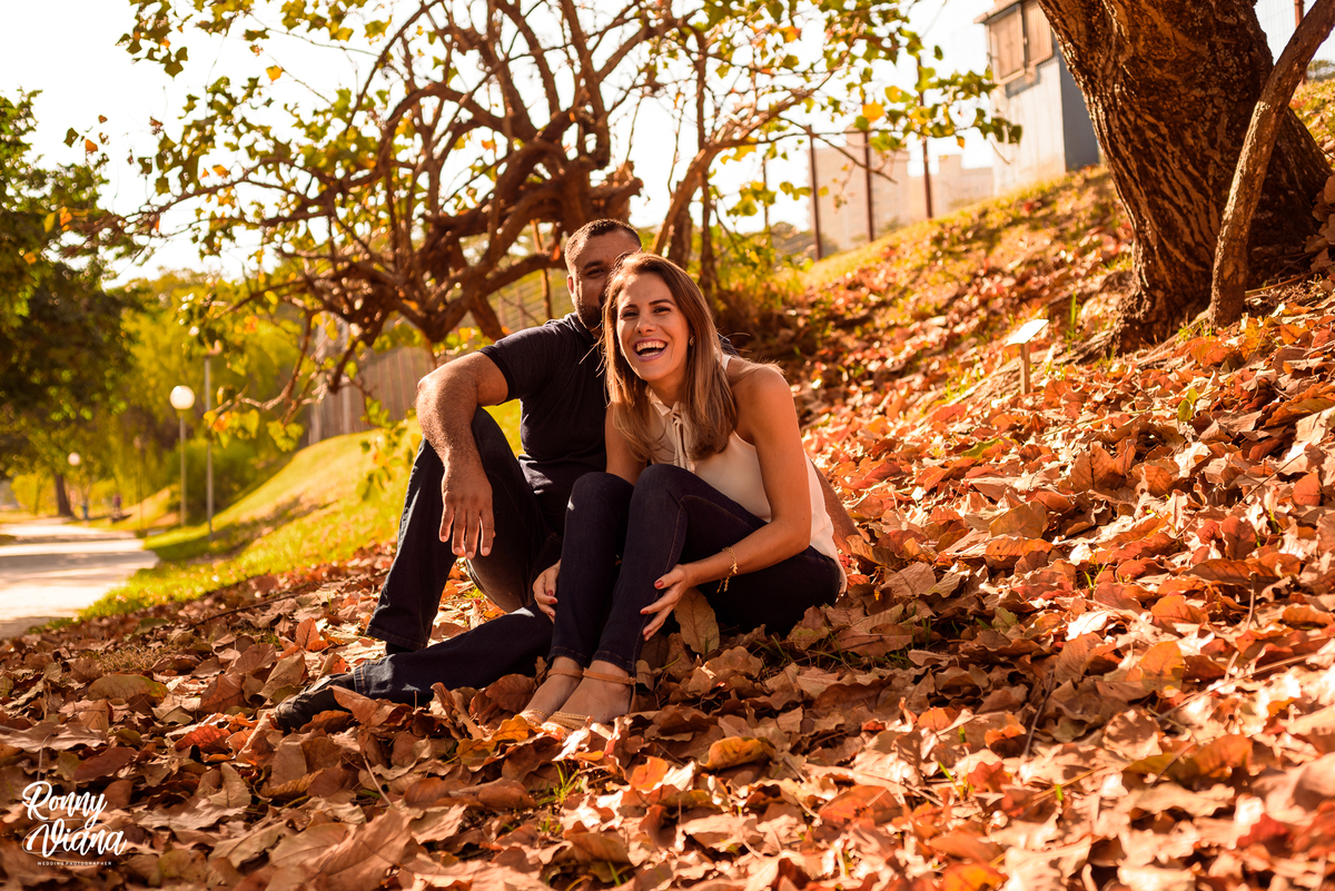 Mamae dando risada com camisa branca e calça preta pai abraçando a mãe