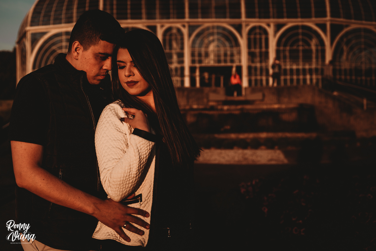 Noivo abraçado com a noiva no por do sol em frente ao Jardim Botânico na cidade de Curitiba PR foto Ronny Viana