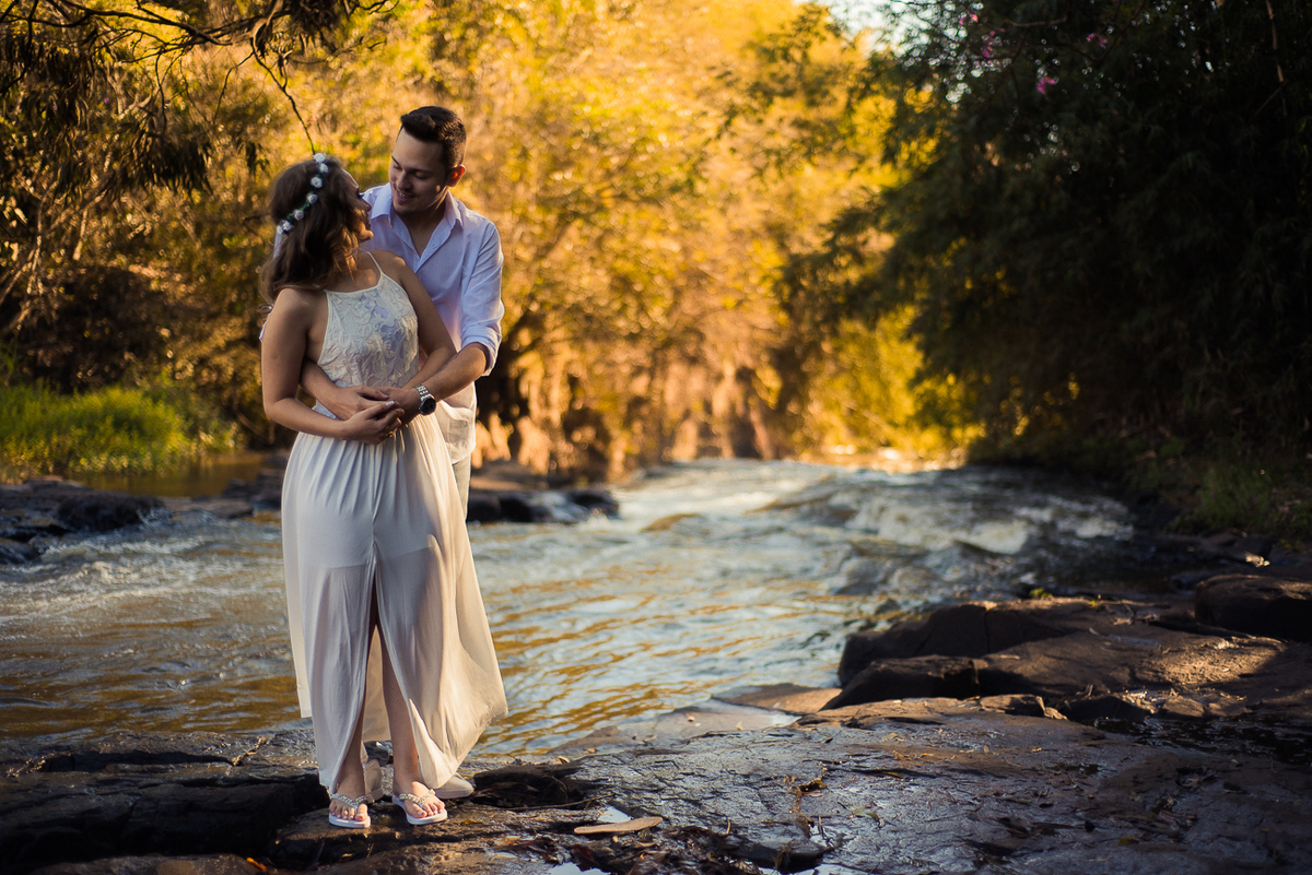 casal abraçado em cima da pedra na cachoeira noiva com vestido branco para ensaio pré wedding por Ronny Viana