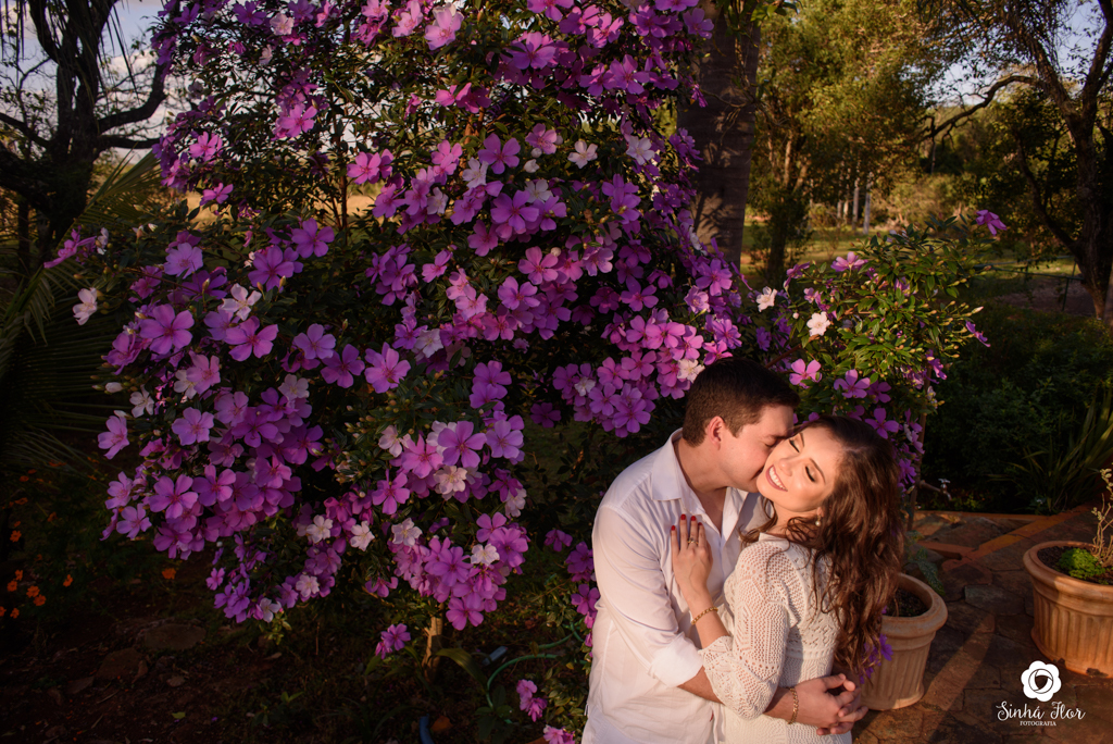 Casal de noivos, Daniele e Thiago, cheiro no pescoço próximo a árvore florida em Dourados - MS, Sinhá Flor Fotografia
