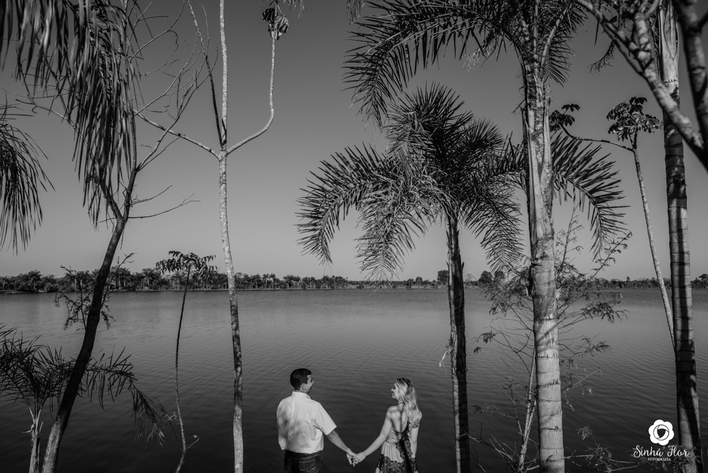 Casal de noivos, Carina e Rodolfo, de mãos dadas ao fundo do lago em Itaporã - MS, Sinhá Flor Fotografia