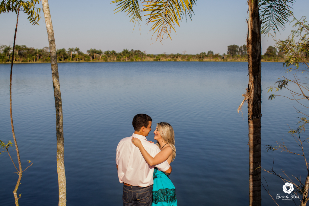 Casal de noivos, Carina e Rodolfo, abraçados de costa ao fundo do lago em Itaporã - MS, Sinhá Flor Fotografia