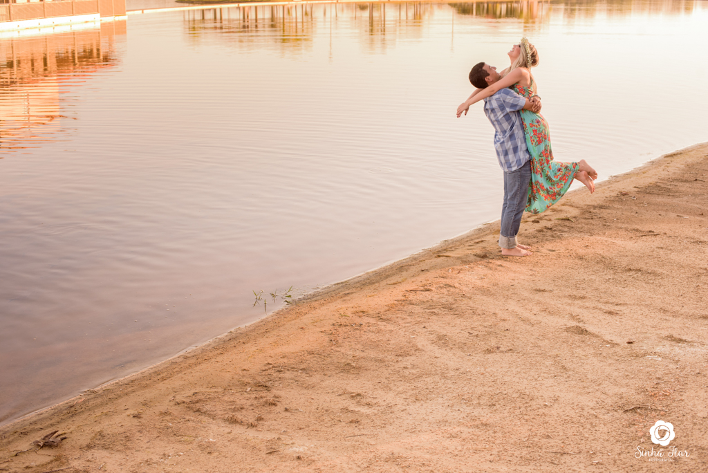 Casal de noivos, Carina e Rodolfo, noivo erguendo noiva ao fundo do lago em Itaporã - MS, Sinhá Flor Fotografia