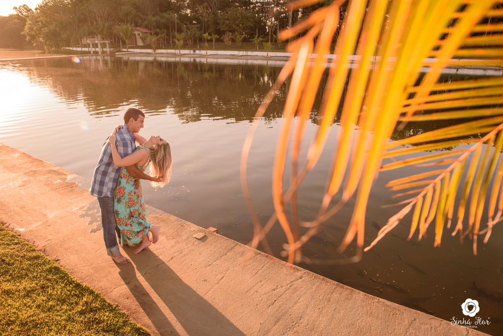 Casal de noivos, Carina e Rodolfo, noivo deitando a noivo próximo ao lago  em Itaporã - MS, Sinhá Flor Fotografia