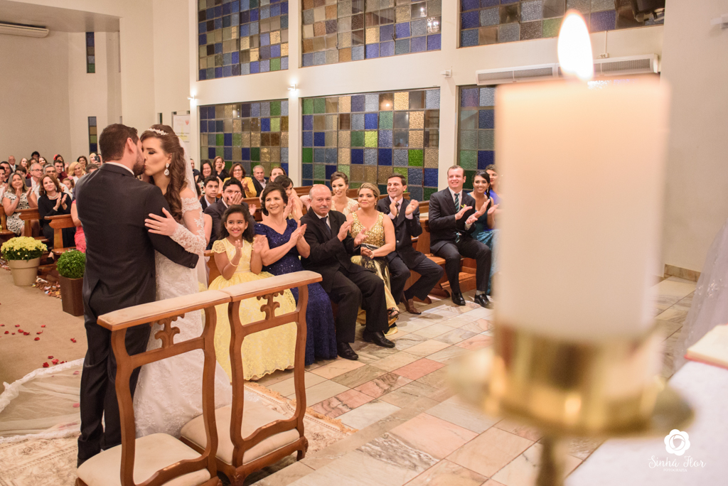Wedding Day, Rosana e Jimmy, momento do beijo e ao fundo os convidados na igreja São Francisco em Dourados - MS, Sinhá Flor Fotografia