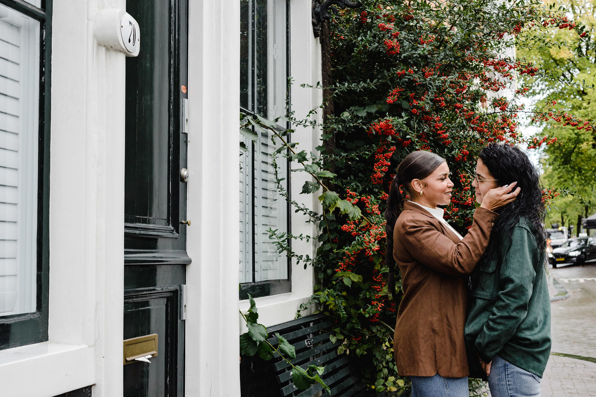 same sex couple laughing in front of an Amsterdam house