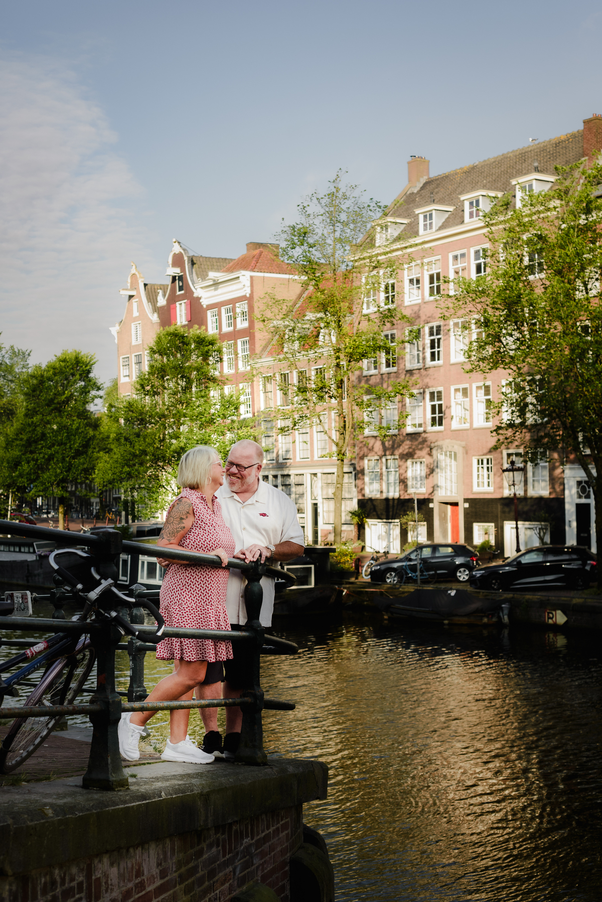 The couple sharing a tender moment, embracing by the side of the canal, with bicycles and charming houses around them.