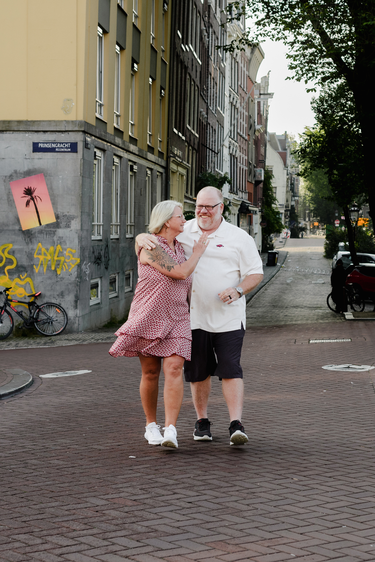 The couple dancing together in a narrow street in Jordaan, with graffiti in the background adding a modern touch.