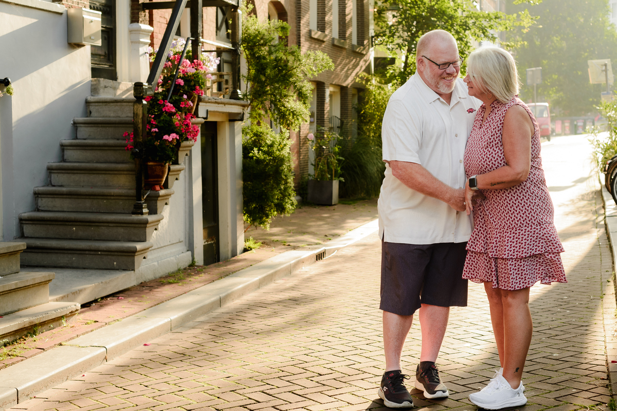 The couple sharing an intimate embrace on a quiet sidewalk, surrounded by the historic charm of Amsterdam.