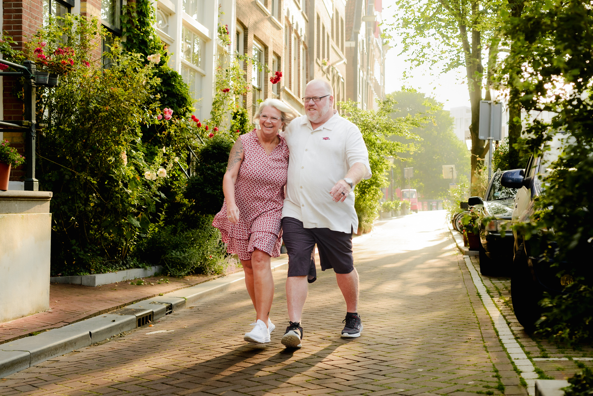  The couple walking arm in arm along a beautiful Amsterdam street, bathed in the warm morning light.
