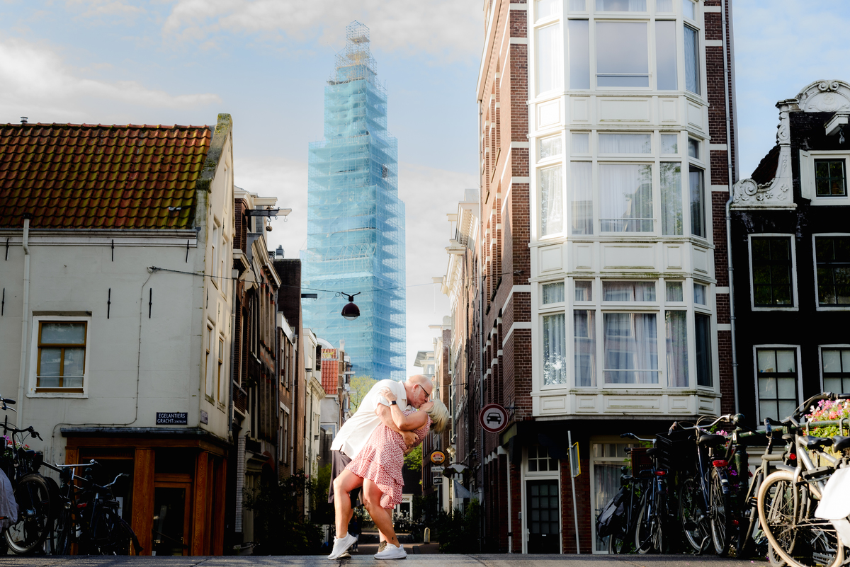 The man romantically dipping his partner in the middle of a quiet Amsterdam street, framed by traditional Dutch houses and the morning light.