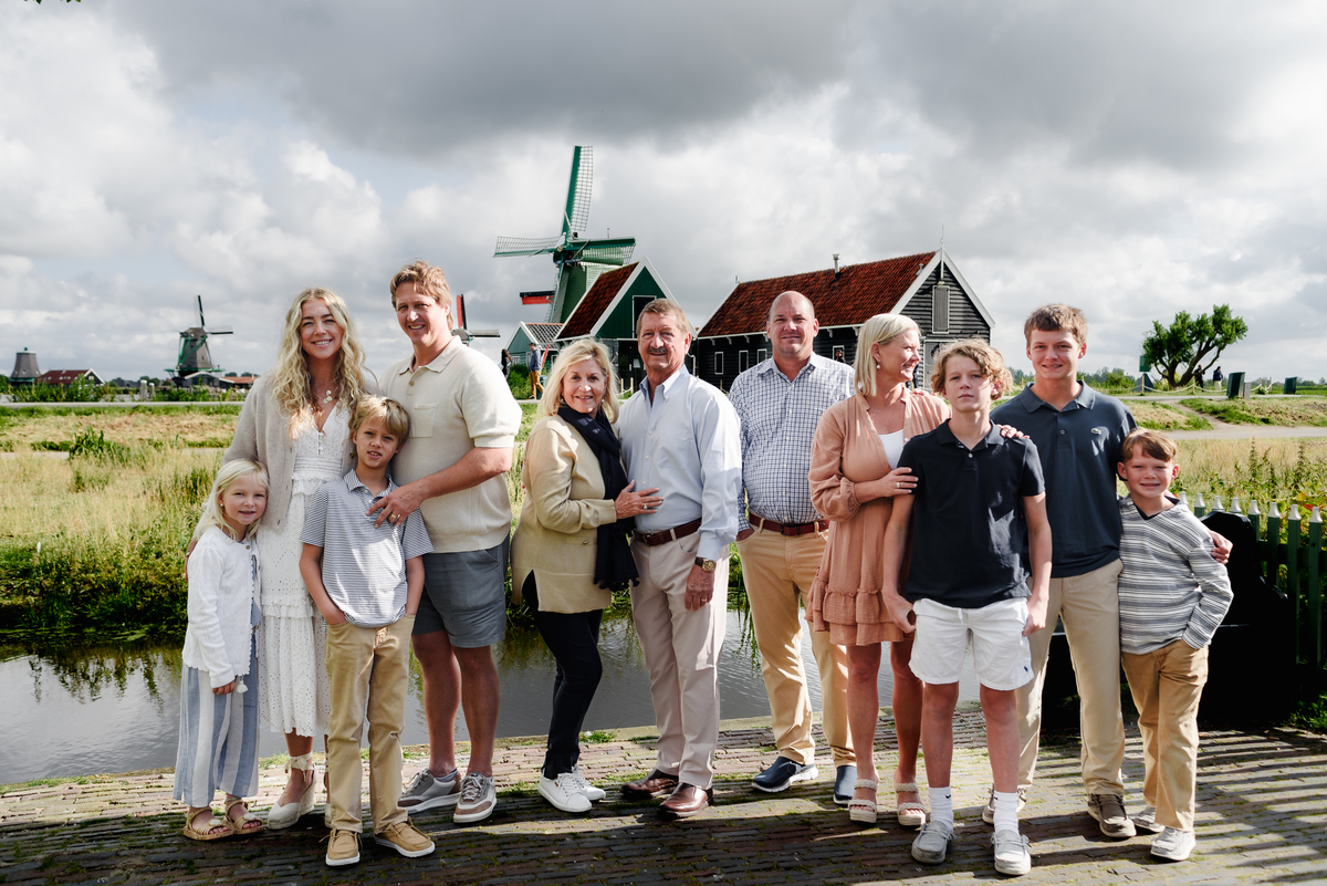 Smiling family gathered in front of iconic Dutch windmills at Zaanse Schans