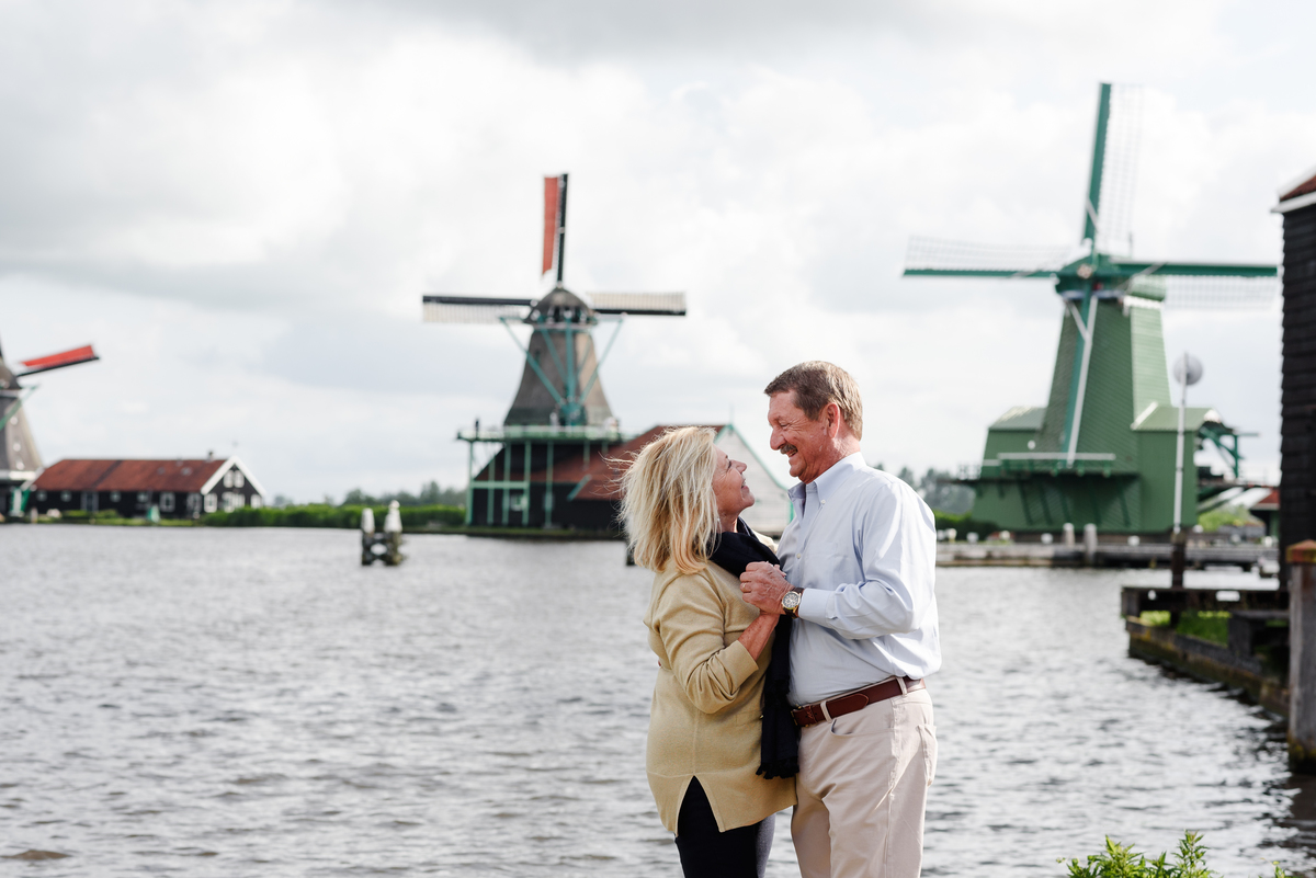 Happy couple posing together with windmills and water at Zaanse Schans