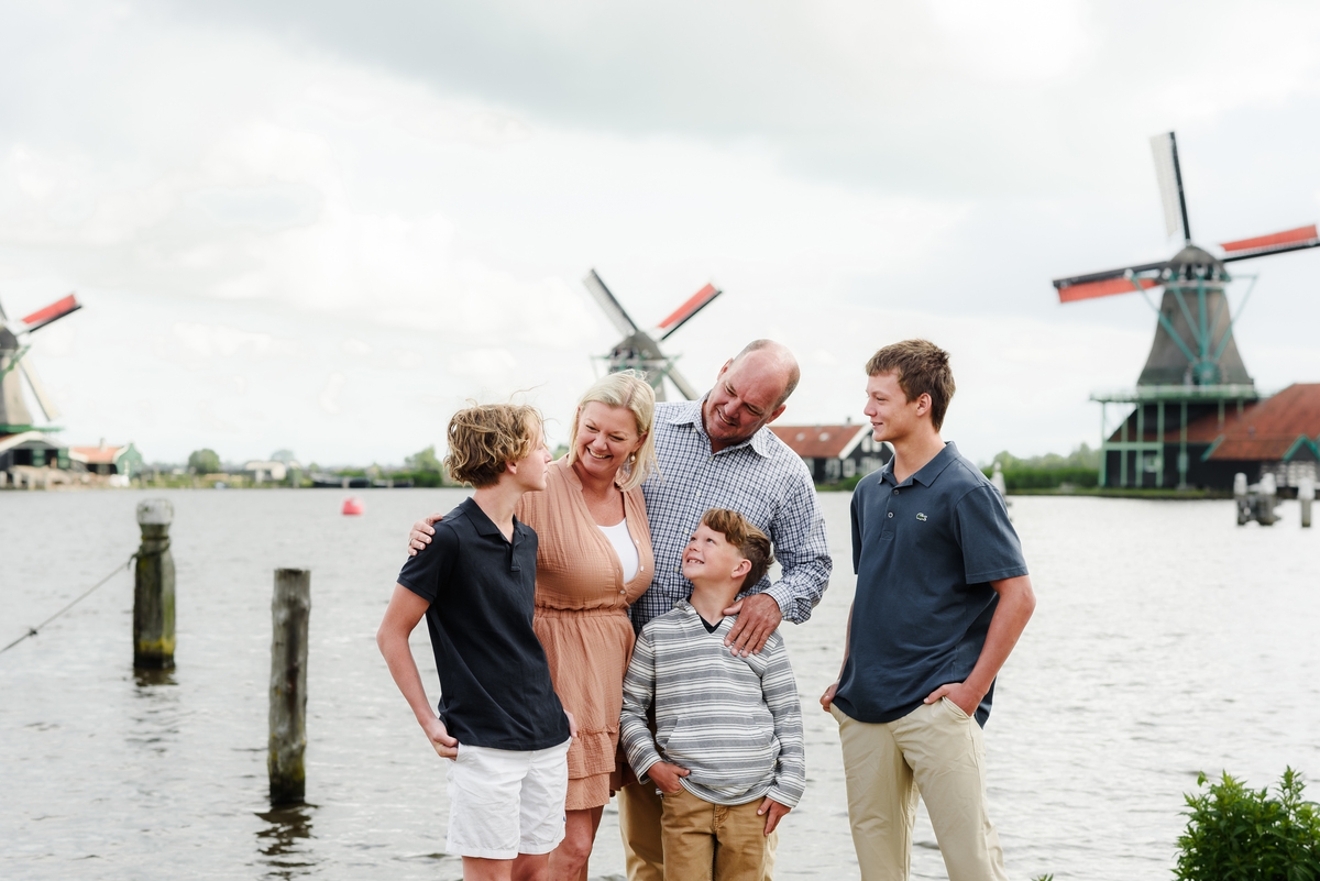 Parents and grown-up children smiling together with Dutch windmills as a backdrop