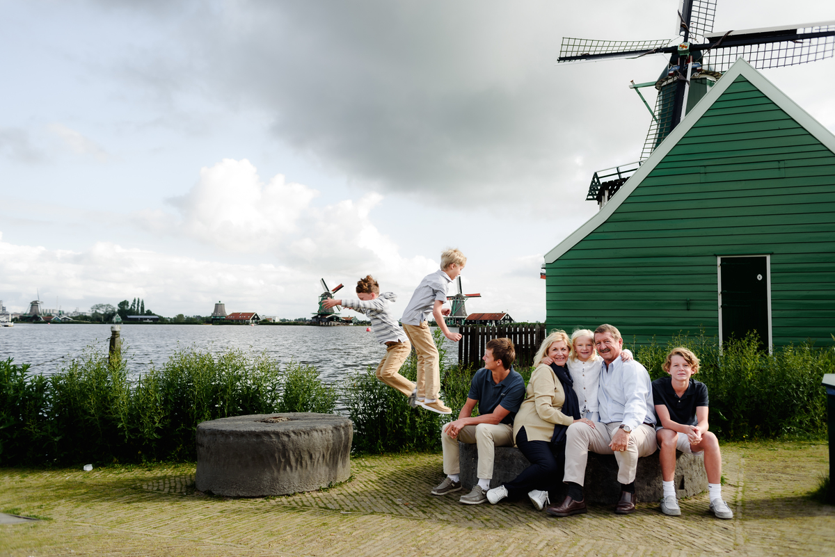 Three generations of a family enjoying a moment together with Dutch windmills in the background. Photo session in Amsterdam