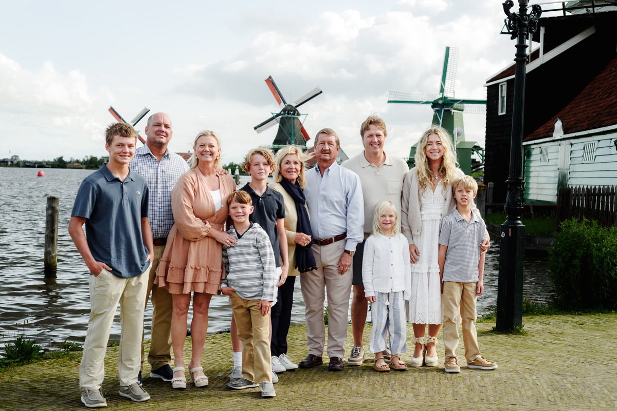 Three generations of a family enjoying a moment together with Dutch windmills in the background.
