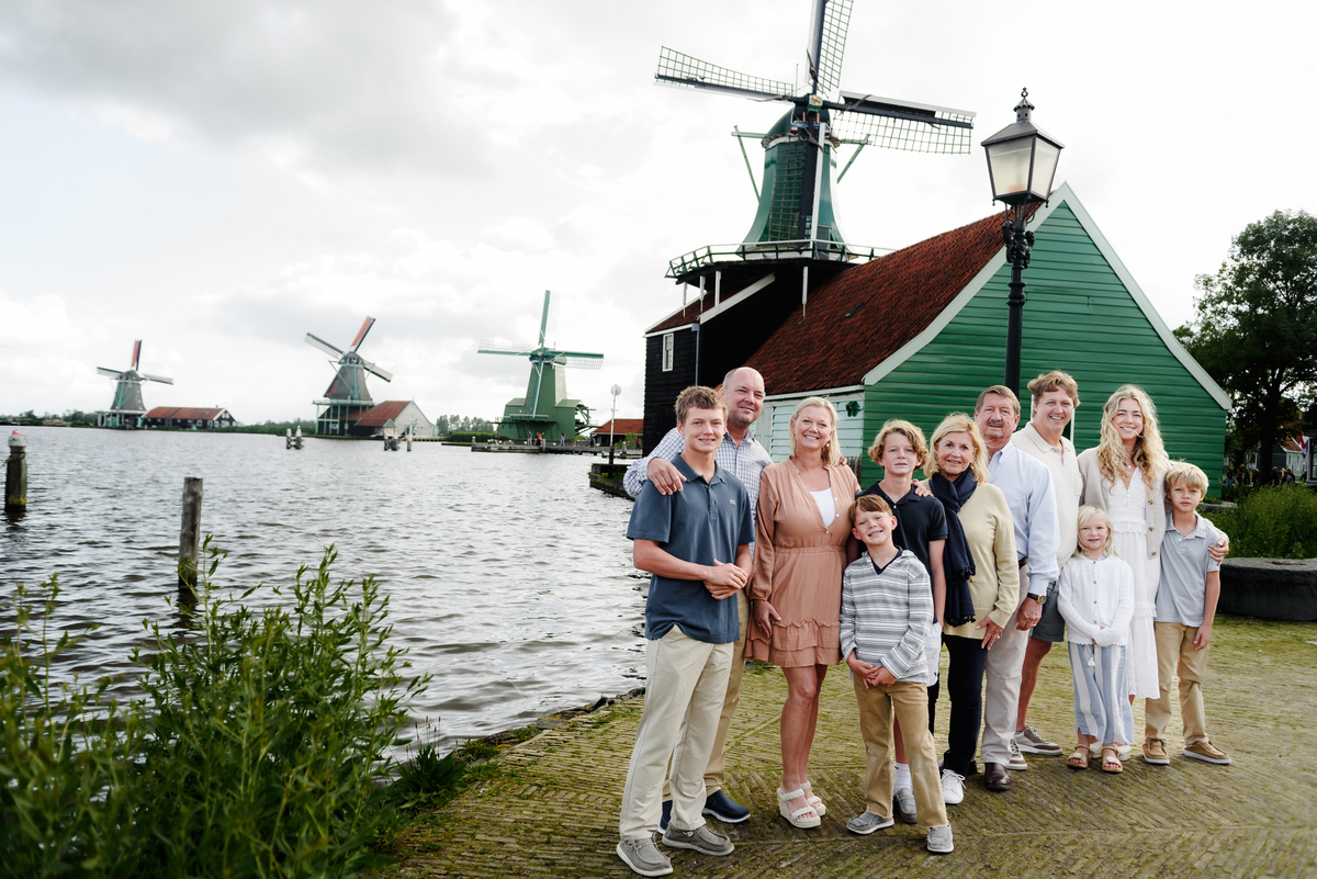 Three generations of a family enjoying a moment together with Dutch windmills in the background.