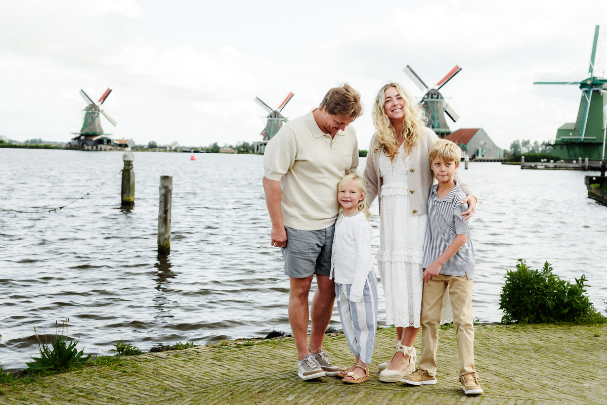 Three generations of a family enjoying a moment together with Dutch windmills in the background. Photo session in Amsterdam