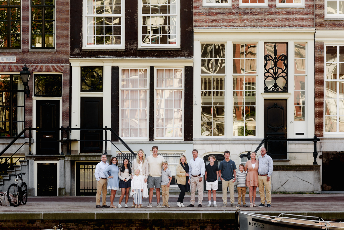 Extended family standing together on a street in Amsterdam, with traditional Dutch architecture behind them.