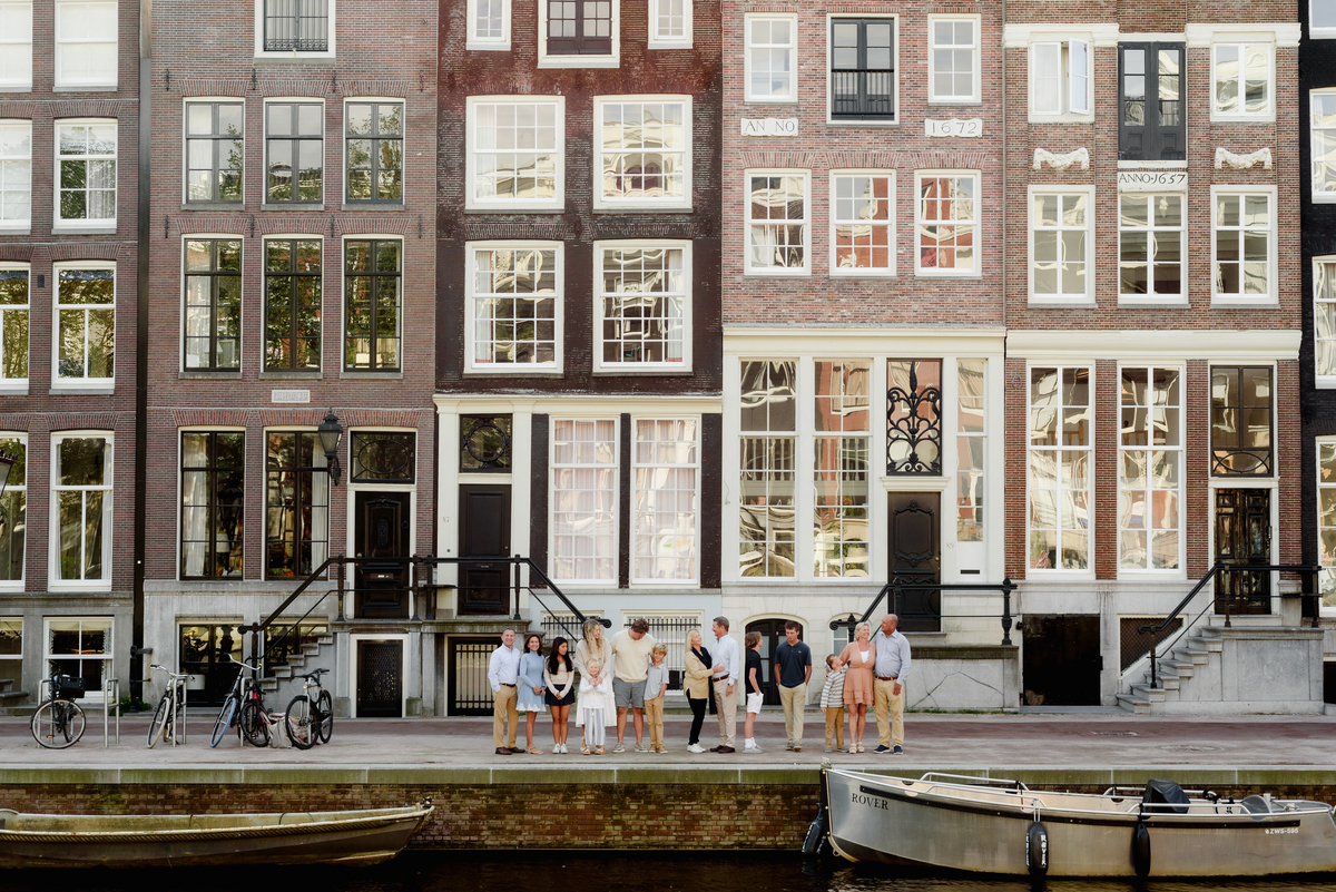 Extended family standing together on a street in Amsterdam, with traditional Dutch architecture behind them.